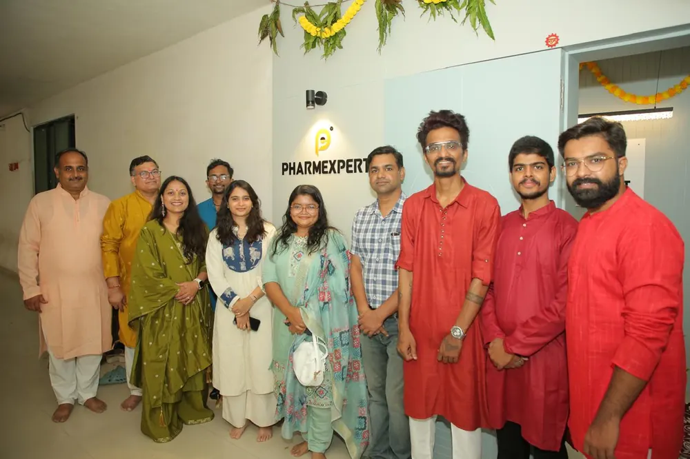 Colleagues gathered beneath the PharmExpert sign in the office during a celebration