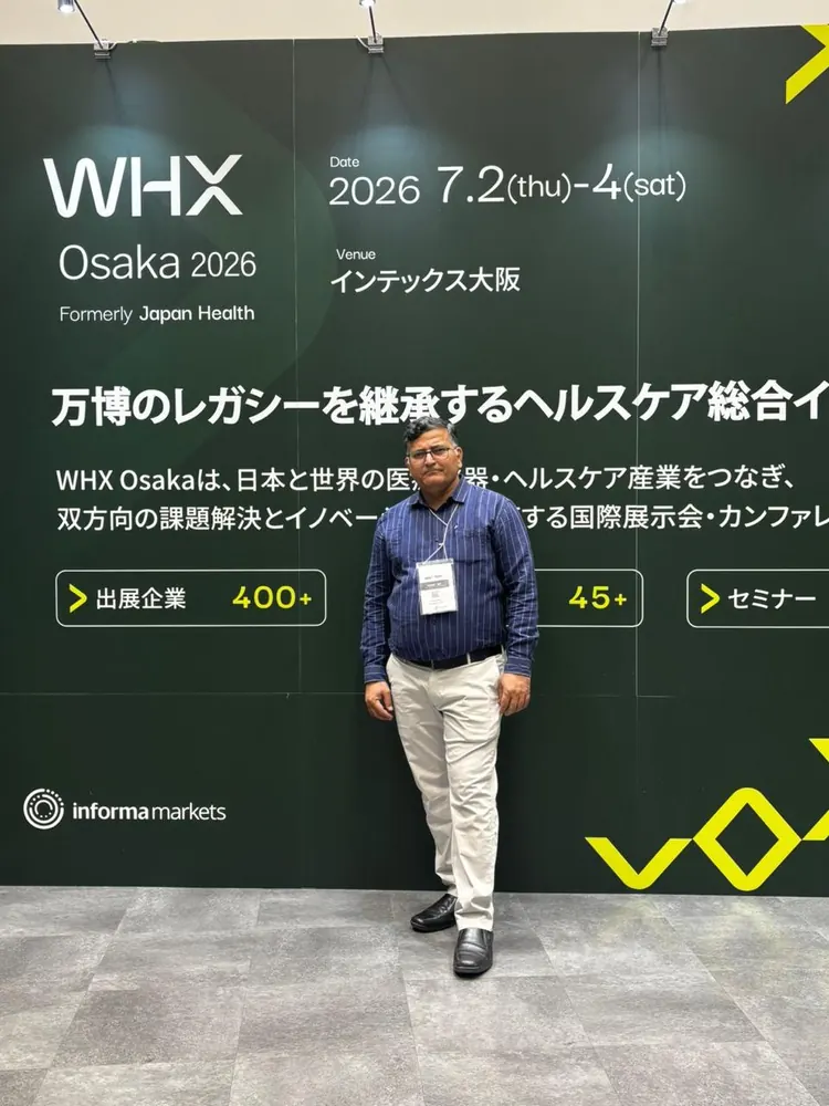 A colleague beside the WHX Osaka signage at the healthcare exhibition